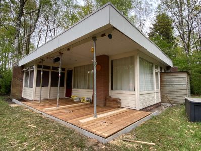 Moderne bungalow met houten terras in een bosrijke omgeving.